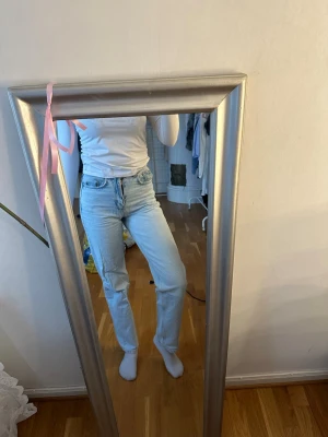 Ljusblå raka jeans med hög midja - Säljer ett par ljusblå jeans med rak passform och hög midja. Klassisk femficksmodell och stängs med dragkedja och knapp. Jeansen har en avslappnad look och är perfekta till vardagsstilen. Materialet är denim i bomull.