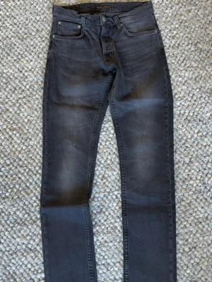 Svarta slim fit jeans från Nudie - Snygga svarta slim fit jeans från Nudie Jeans med klassisk femficksmodell . Jeansen har normal midja och raka ben. Tillverkade i mjuk denim med för extra komfort.
