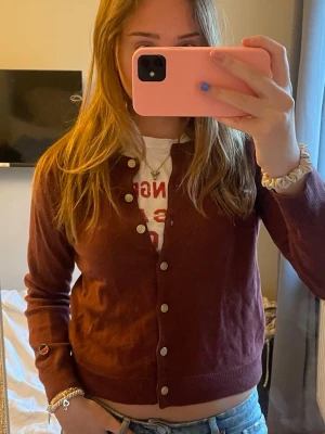 Vinröd kofta från Busnel  - Snygg vinröd kofta från Busnel med guldfärgade knappar framtill och ribbade muddar. Klassisk rak passform och lång ärm. Perfekt att slänga över en t-shirt eller linne för en chill look. Supersnygg och skön! Storlek 40 men är rätt så liten i storleken. Har några hål på ärmen som inte syns så mycket❣️