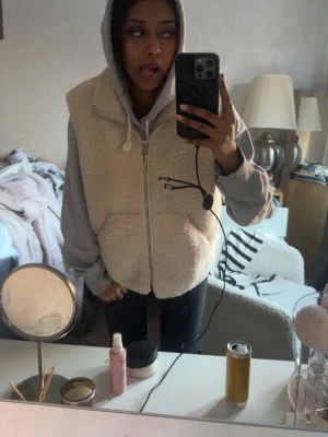 Ljusbeige teddy väst💕 - Mysig ljusbeige pileväst med dragkedja framtill och två stora fickor. Västen har en fluffig teddystruktur som ger en avslappnad och trendig look. Perfekt att slänga över en hoodie för extra värme. Färgen är neutral och lätt att matcha.