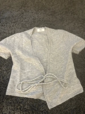 Ljusgrå stickad kofta med knytband - säljer min stickade kofta med korta ärmar från ginatricot då ja aldrig använt den 