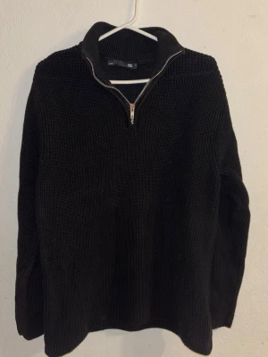 Svart stickad tröja med half zip - Mysig svart stickad tröja med hög krage och half zip-dragkedja. Tröjan har lång ärm och en enkel, stilren design som passar perfekt till kyligare dagar. Ribbstickad struktur för extra komfort och värme. Inte använt den så mycket ligger bara där och vill säljas 