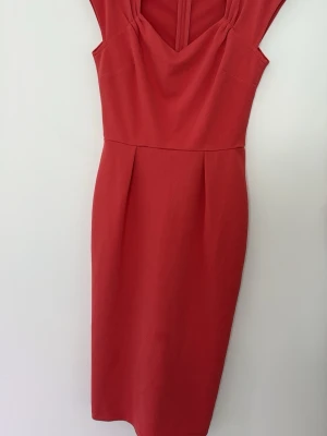 Röd klänning från NLY Eve - Snygg röd klänning från NLY Eve med v-ringad hals och figurnära passform. Klänningen har breda axelband och en stilren, enkel design som passar perfekt till speciella tillfällen. Tillverkad i ett mjukt och följsamt material. Sömmen har börjat släppa lite men är inga hål någonstans vad jag ser. Se sista bilderna.