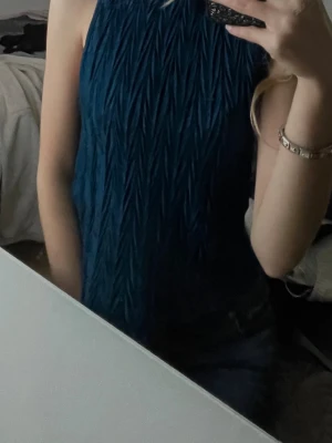 Mörkblå ärmlös topp med struktur - Snygg mörkblå topp med coolt strukturerat mönster och ärmlös design. Perfekt till jeans eller kjol för en trendig look. Materialet känns mjukt och har ett lätt glansigt intryck.