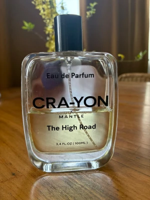 Crayon The High Road Eau de Parfum 45ml - Ca 45 ml kvar.Toppnoter: Fikonblad: Fräsch, fruktig och varm. Salvia: Kryddig, fräsch, kamferaktig doft. Cannabis: Jordig, grön och lugnande. Hjärtnoter: Kokosnöt: Söt och krämig med en nötaktig ton av vanilj. Viol: Mjuk, pudrig, feminin och flirtig. Lilja: Inbjudande och subtil med en lätt citrusaktig underton. Basnoter: Amber: Sensuell, mjuk med en subtil kryddig underton. Vetiver: Jordig, läderaktig och rökig. Cederträ: Djup, träig och autentisk. Musk.