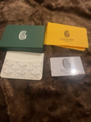 Vit kortfodral från H&M - Supersnyggt vitt kortfodral från H&M med häftiga mönster. Fodralet har flera kortfack och är gjort i läder. Perfekt för dig som vill ha en simpel och fin accessoar i fickan. Kommer med ask och putsduk.