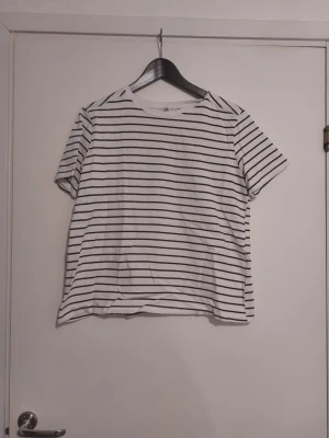 Randig t-shirt från Zara - Vit t-shirt med svarta horisontella ränder från Zara. Klassisk rund halsringning och korta ärmar. Tillverkad i mjuk bomull, perfekt för en avslappnad och stilren look.