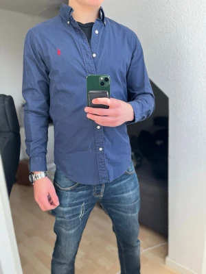 Ralph Lauren skjorta  - Klassisk marinblå skjorta från Ralph Lauren! Perfekt nu till sommaren☀️☀️ Skjortan har långa ärmar, vita knappar och är tillverkad i bomull. Perfekt för en stilren och avslappnad look. Tveka inte på att höra av er vid funderingar✅storlek 6 så den sitter som S!