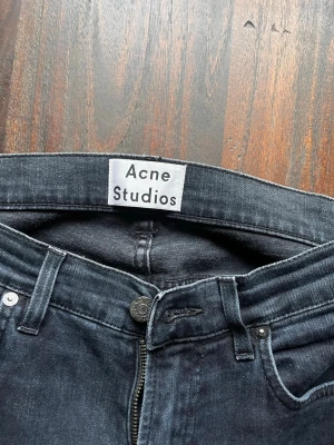 Svarta skinny jeans från Acne Studios - Snygga svarta skinny jeans från Acne Studios med klassisk femficksdesign och dragkedjegylf. Jeansen har en smal passform och är tillverkade i stretchigt denimtyg för en bekväm känsla. Perfekta för en trendig och stilren look.