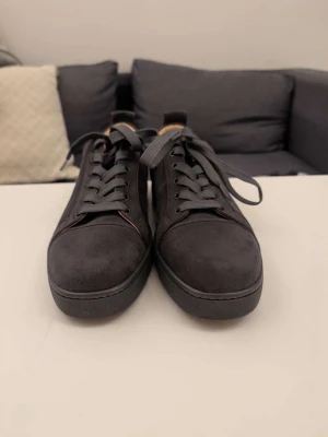 Christian louboutins - Stilrena mörkgrå sneakers med mocka-liknande material och mörkgråa skosnören. Låg modell med rund tå och diskret design. Insidan är ljusbrun vilket ger en snygg kontrast. Perfekta för dig som gillar minimalistisk stil.