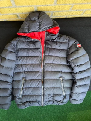 Colmar navy - Snygg mörkblå dunjacka från Colmar med röd insida och huva. Riktigt bekväm och perfekt för svalare dagar. 