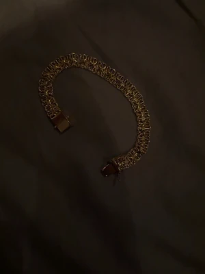 Guldigt kedjearmband, xlänk  - Snyggt armband i guldfärgad metall med bred kedjedesign. Armbandet har ett rektangulärt spänne och en flätad look som ger en trendig känsla. Perfekt accessoar för att lyfta din outfit.