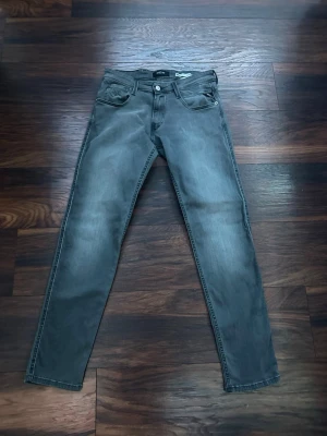 Grå slim fit jeans från Replay - Snygga grå slim fit jeans från Replay med klassisk femficksdesign och diskreta slitningar. Jeansen har normal midja, dragkedjegylf och raka ben. Modell Anbass, slim fit. Storlek W30 L32. Endast använda fåtalet gånger. Hör av dig vid frågor 😃