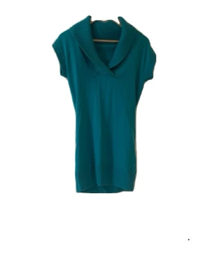 Turkos stickad topp med krage - Snygg turkos stickad topp med bred krage och korta ärmar. Perfekt att styla med jeans eller kjol för en trendig look. Ribbstickade detaljer vid krage och nederkant ger extra stilpoäng. Materialet känns mjukt och bekvämt.