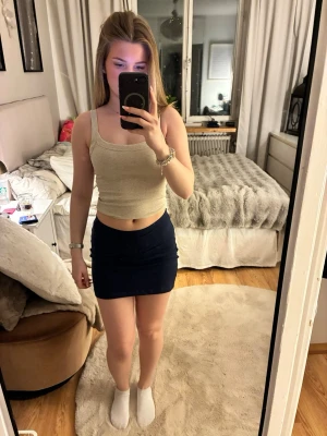 Mörkblå kortkjol i bomull - En enkel och stilren mörkblå kortkjol i bomull. Kjolen har en tight passform och slät design utan synliga detaljer, perfekt för att skapa en clean look. Passar dig som gillar minimalistiskt och klassiskt mode.