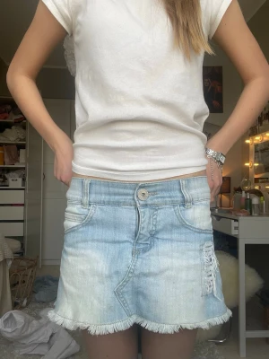 Ljusblå jeanskjol med fransad kant - Säljer en ljusblå jeanskjol med fransad nederkant och slitningar på ena sidan. Kjolen har klassiska jeansfickor fram och bak samt knapp- och dragkedjestängning. Perfekt för en varm sommardag☀️