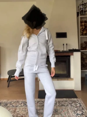 Grått mjukisset med dragkedja - Mysigt grått mjukisset med luvtröja och matchande byxor. Tröjan har dragkedja framtill, fickor och justerbar huva med snören. Byxorna har resår i midjan för skön passform. Endast använda 1 gång och säljer då jag har beställt ett marinblått 🤍