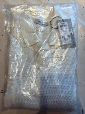 Vit stickad tröja med krage från ONLY - Snygg vit stickad tröja från ONLY med klassisk krage och grovstickat mönster. Tröjan har lång ärm och är tillverkad i ett mjukt material som passar perfekt för kyligare dagar. Enkel att matcha med både jeans och kjol. Skriv för minsta lilla fråga. Det är en T-shirt 