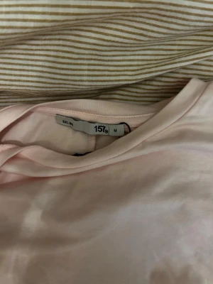 Ljusrosa långärmad topp 157 - En enkel och stilren ljusrosa långärmad topp från 157. Tillverkad i mjuk bomull med rund halsringning och normal passform. Perfekt att matcha med jeans eller kjol för en clean look.