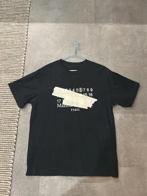Svart Maison Margiela t-shirt - Hejjj och välkomna till liljestrands nu säljer vi en Maison margiela t shirt inprincip ny använd fåtal gånger osäker på äktehet köpt på vinted så vet ej men väldigt bra kvalitet och kan gå ner i pris de är storlek 46 vilket motsvarar typ M-L skulle jag säga kom med frågor osv mvh lilejstrand