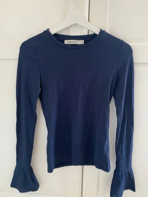  Långärmad marinblå tröja💙 - Jättefin blå långärmad tröja med volanger på ärmarna. Köpt på sellpy men jag har inte använt den, tröjan är är i jättefint skick. Hör av om ni har frågor, pris kan diskuteras💙💙