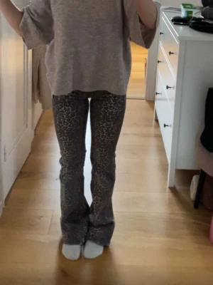 Bruna leopardmönstrade jeans - Snygga bruna jeans med leopardmönster och utsvängda ben. Perfekta för dig som vill sticka ut med ett trendigt djurmönster. Mjukt och stretchigt material som sitter bekvämt hela dagen.