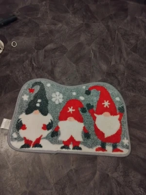 Julmatta med tomtar och snöflingor - Söt julmatta i mjukt material med motiv av tre tomtar i rött, vitt och grått samt snöflingor. Mattan har en böjd form och halkfri baksida, perfekt att lägga i hallen eller badrummet för att skapa julstämning. Finns fler på min sida. Kanske behlver sig en tvätt 