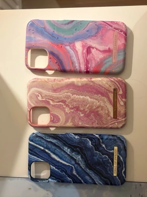 3 färgglada mobilskal från iDeal of Sweden - Säljer tre snygga mobilskal från iDeal of Sweden med marmorerade mönster. Ett i blått, ett i rosa/beige och ett i pastellfärger med lila, rosa och grönt. Alla har en glansig finish och är gjorda i hårdplast. Perfekt för dig som vill ha en unik look på mobilen. Skalen passar både iPhone 11 och xr!! Skalet längst åt höger är helt nytt har till och med lådan kvar till skalet!🙌🙌🙌