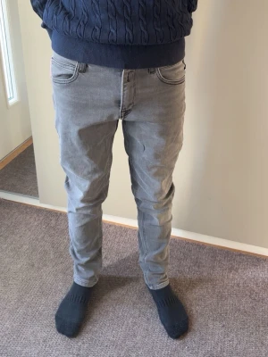 Gråa slim fit jeans replay - Säljer ett par gråa slim fit jeans från replay med klassisk femficksdesign och snygga sömdetaljer på bakfickorna. Jeansen har normal midja och är tillverkade i mjuk bomullsdenim med lite stretch för extra komfort. Storlek 158 cm. De är knappt använda! Lappen på baksidan av jeansen har gått sönder och är ihopsydd lite slarvigt. Hör av er vid intresse! 