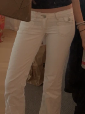 Vita bootcut jeans med låg midja - Nelly  - Säljer ett par vita bootcut jeans med låg midja och klassiska fem fickor. Jeansen har en snygg passform och stängs med dragkedja och knapp. Perfekta för dig som vill ha en fräsch och trendig look. Dom är från Nelly,ny pris 700kr 