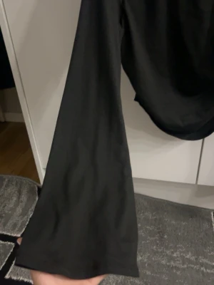 Svart topp med utsvängda ärmar - svart topp med långa utsvängda ärmar och rynkade detaljer vid magen. Tunn och mjuk i materialet. 