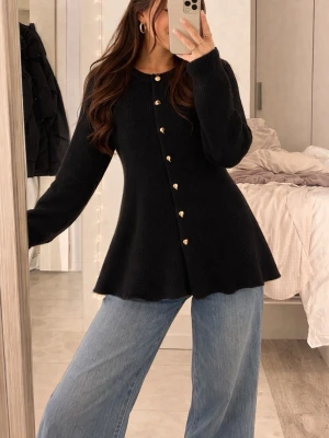 Svart kofta med hjärtformade knappar - Säljer en svart, långärmad kofta med utsvängd passform och hjärtformade guldfärgade knappar. Koftan har rund halsringning och är stickad i ett mjukt material. Perfekt för att ge din outfit en söt touch.