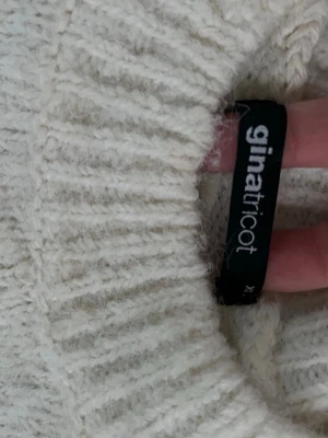 Vit polotröja från Gina Tricot - Mysig stickad polotröja i offwhite från Gina Tricot. Tröjan har en hög krage, långa ärmar och ribbade muddar vid ärmslut och nederkant. Perfekt för lager på lager och en clean look till höst och vinter.