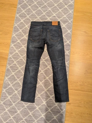 Mörkblå Jack & Jones jeans - Säljer ett par mörkblå Jack & Jones jeans med raka ben. Byxorna är i storleken 28/32 och modellen Slimstraight/Tim. Jeansen är sjukt snygga och har oranga fickor som är en sjukt snygg detalj! 🔥 Kontakta gärna vid frågor! 😊