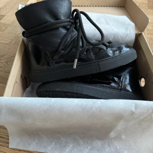 Inuikii - Vinterskor från Inuikii i modellen ”Gloss Black”. Skorna är i stl 38 och är varmt fodrade. De har använts men är i gott skick och har inga skador.  Nypris ligger på 3500kr. ❣️❣️ 