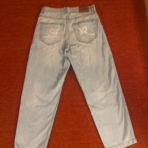 Rocawear baggy jeans - Rocawear baggy fit jeans med broderingar på bakfickorna. Väldigt bra skick förutom lappen på insidan som lossnat lite men det syns inte och kan tas bort eller lagas. Måtten är 41x104x30x21 cm (midja/längd/lår/benöppning).  Skriv för fler bilder.