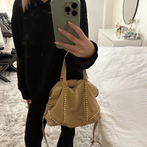 Beige/rosa väska - Beige/rosa väska med guldiga nitar! Gammal kollektion från zara. Köpte här på plick och den är rätt sliten men ändå såå snygg! Säljer pga har för många väskor och denna används för lite för att kunna ha kvar! Säljer även en likadan fast i svart🩷