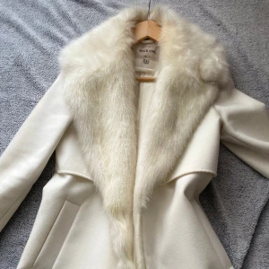 Kappa med fake pälsk - Jättefin kappa från riverisland, köpt för några år sedan. Enbart använt den 2 ggr, legat i gareroben sen dess. Jättefin med inga defekter 