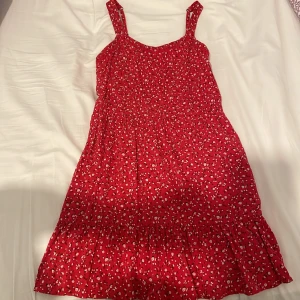 Röd klänning - Jättefin röd klänning med blommönster från abercrombie. Den har storlek 13-14 men skulle säga att den är XS-S. Den är väldigt stretchig och har justerbara band. Säljs då den inte kommer till användning längre💗