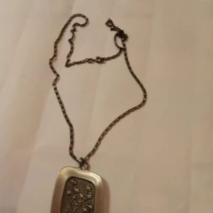 Tenn halsband mönstrad Silverfärgad . - Fint gammalt Tenn halsband mönstrat fram med blomma och stämpel bak på medaljongen .fint skick .hämtas i Skene alt skickas .