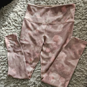 Rosa leggings med mönster - Ett par rosa leggings med ett subtilt mönster i olika nyanser av rosa och beige. Leggingsen har hög midja och är tillverkade i ett stretchigt material som ger en bekväm passform.mobilficka på insidan