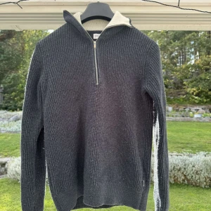 Stickad Halfzip - Fin mörkblå/grå stickad halfzip tröja med vit inner krage, storlek S men passar även M. Tröjan är i bra skick, lite nopprig men går att få bort. 