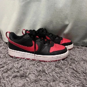 Svart och röd Nike sneakers - Ett par svart och röd Nike sneakers med snörning. 