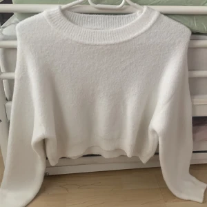 Vit stickad tröja från Zara - En vit stickad tröja från Zara med rund halsringning och långa ärmar. Tröjan har en ribbad kant vid halsen, ärmsluten och nederkanten.