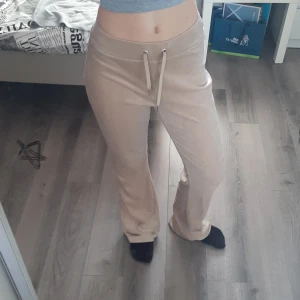 Beige mjukisbyxor från Gina Tricot - Ett par beige utsvängda mjukisbyxor från Gina Tricot i storlek XS. De är i velour och är stretchiga. Finns även fickor baktill. Det är resårmidja och knytbara, vilket gör de perfekta för avslappnade tillfällen.💕