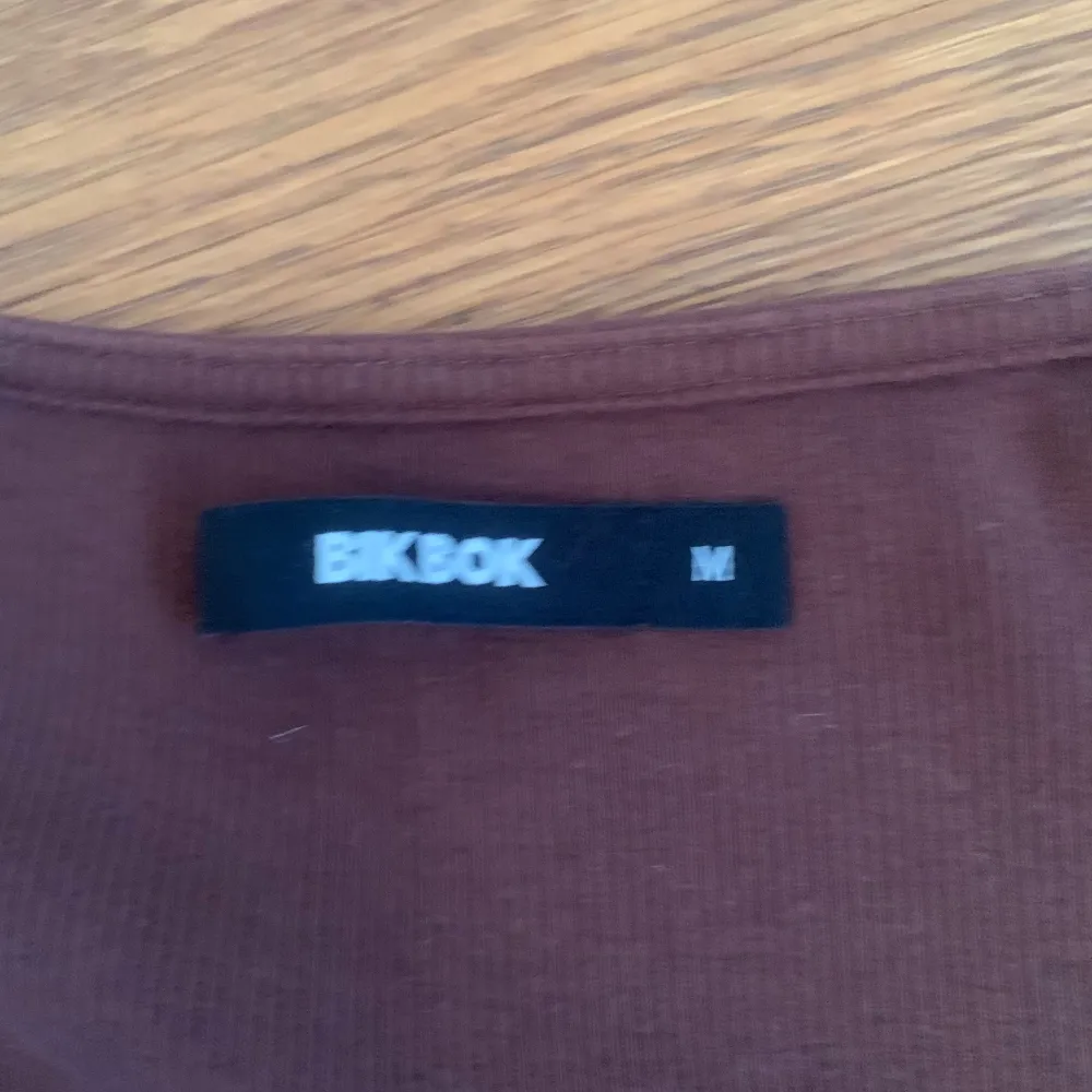 En brun topp från Bik Bok med korta ärmar och en fyrkantig halsringning. Toppen är tillverkad i ett ribbat material och har en normal passform.. Yläosat.