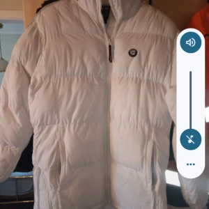 Dam jacka vit/grå med luva stl L - Fin vit/grå dam jacka med luva stl L med gråa ränder på ärmarna.knäppes med dragkedja. Fint skick.nytt snöre i luvan behövs.