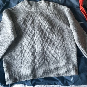 Grå stickad tröja - Grå tjock stickad tröja med mönster på framsidan som ej kommit till användning. Använd ett fåtal gånger men i väldigt bra skick. Tröjan är i storlek xs men är som en Large eller Medium.