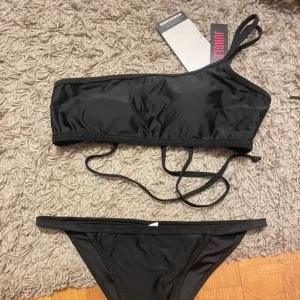 Svart glitter bikini - One shoulder bikini med glittrig kant, aldrig använd för tyvärr för liten. Prislappar kvar