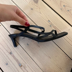 Svarta sandaler med klack - Eleganta svarta klackar med smala remmar.